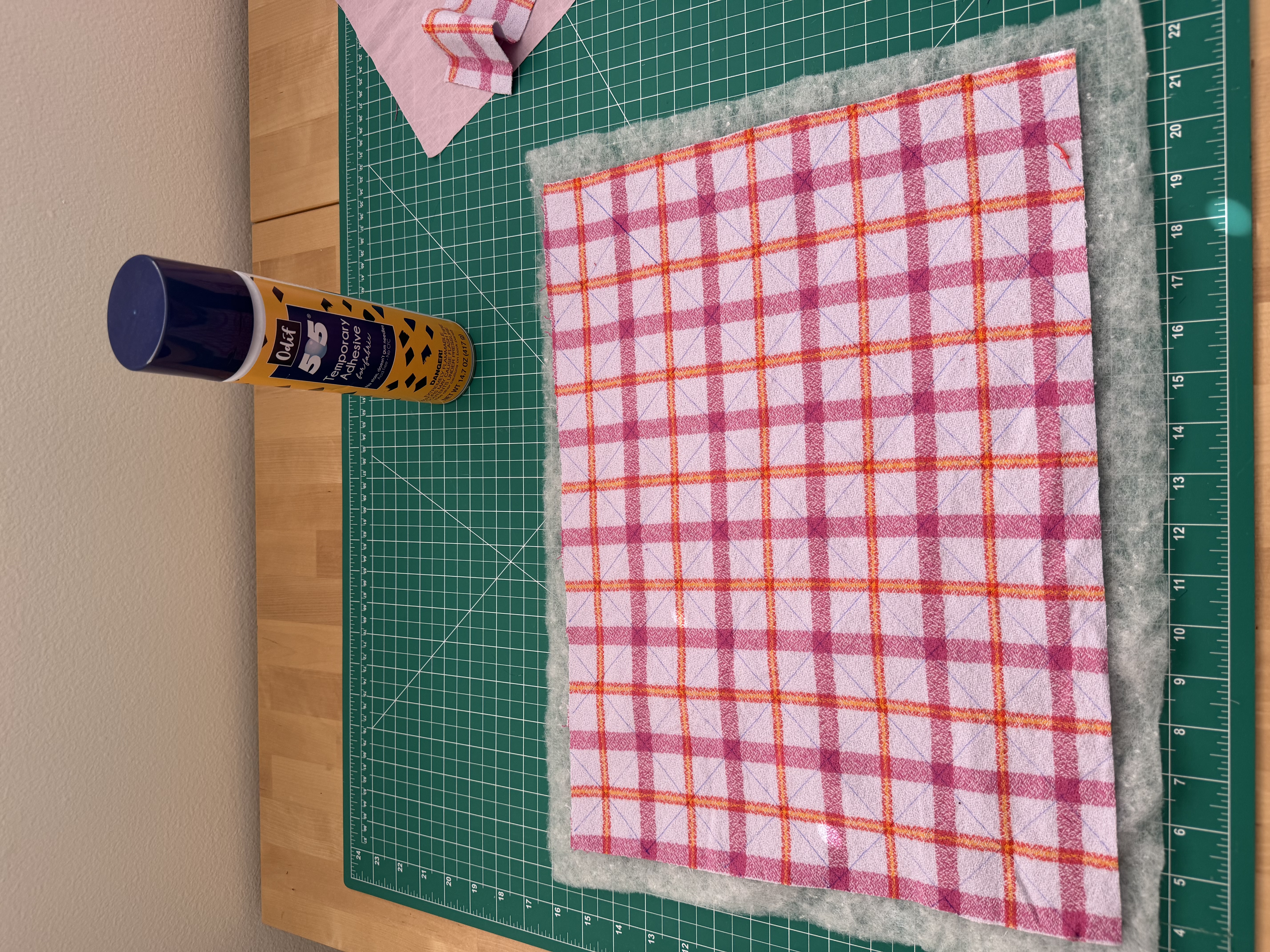 Fabric, batting, and a can of Odif 505 temporary fabric adhesive spray laid out before quilting the book sleeve